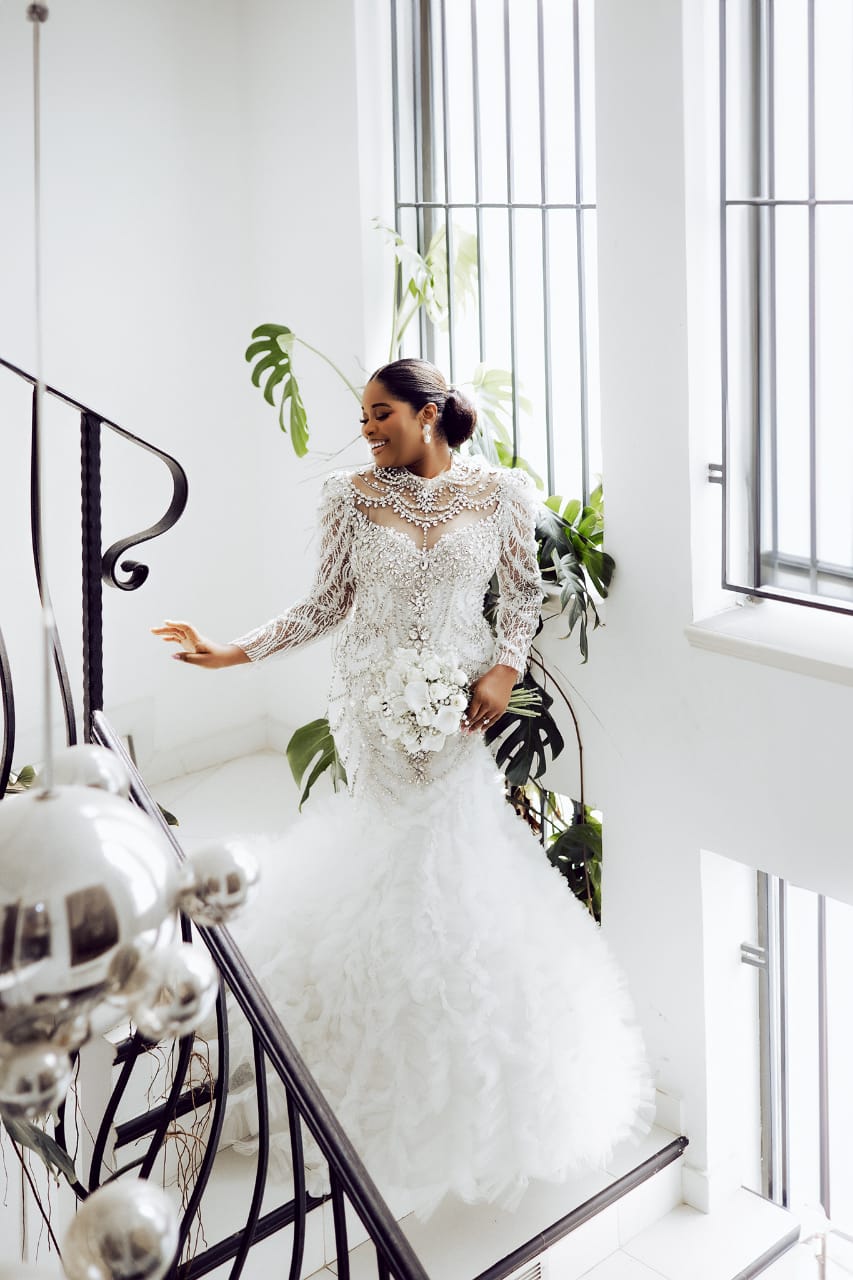 standing bride in white gown along a staircase